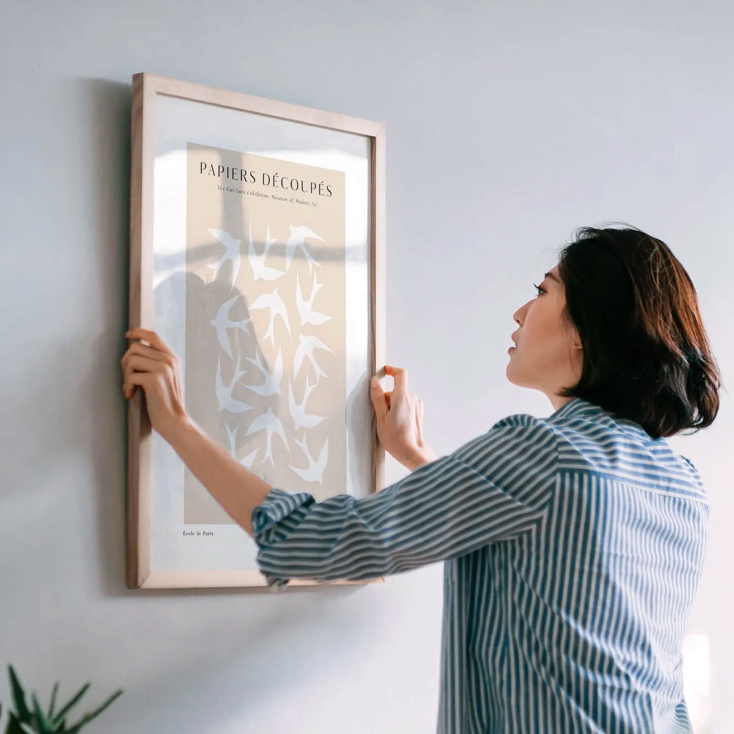 Woman hanging a framed artwork on a wall