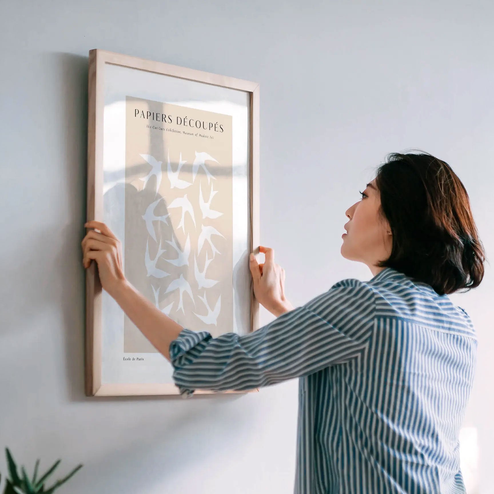 Woman hanging a framed artwork on a wall