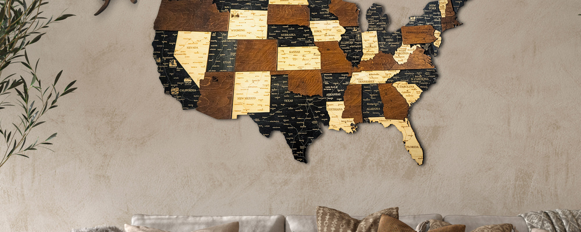 Wooden map of the United States on a beige wall above a sofa.